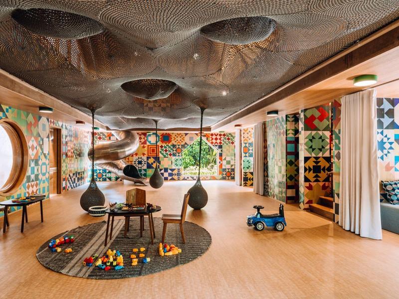 Bunter Kinderspielraum mit Holzfußboden, Spielzeug und Fenster mit Rundfenstern.