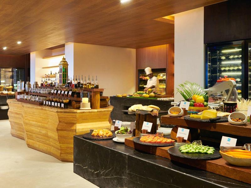 Buffet mit Käse, Obst und Wein, moderne Holz- und Marmoraufsätze, warme Beleuchtung, saubere Anordnung.