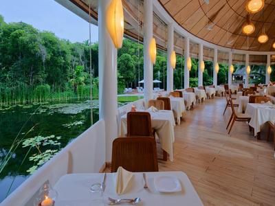 Ristorante all'aperto con tavoli bianchi che si affacciano su uno stagno in un hotel.