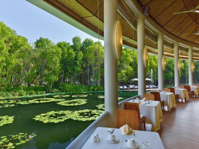 Geschwungener Außenbereich eines Restaurants mit Seeblick und Tischen mit weißen Tischdecken.