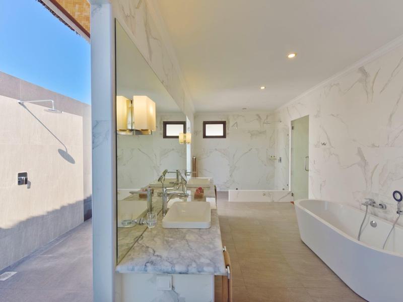 Luxuriöses Badezimmer mit freistehender Badewanne und großer Glasfront mit Blick ins Freie.