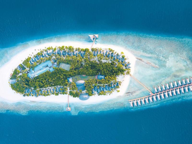 Luftaufnahme einer tropischen Insel mit weißem Sandstrand und Überwasserbungalows.