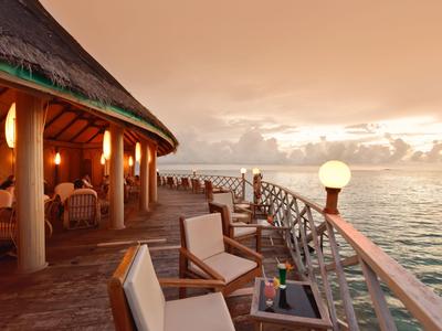 Hotelterras met zitgelegenheid en uitzicht op de oceaan bij zonsondergang