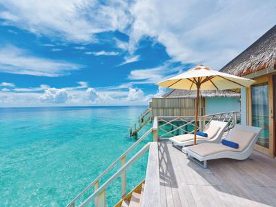 Terras met ligstoelen en parasol boven turquoise zee onder blauwe lucht