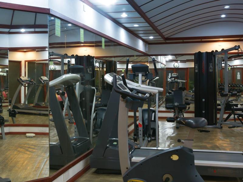 Innenraum eines Fitnessstudios mit Laufbändern, Spiegelwänden und verschiedenen Kraftgeräten.