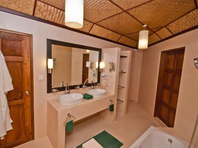 Großes Badezimmer mit Holzdecke, zwei Waschbecken, Spiegel, Badewanne und zwei Holztüren.