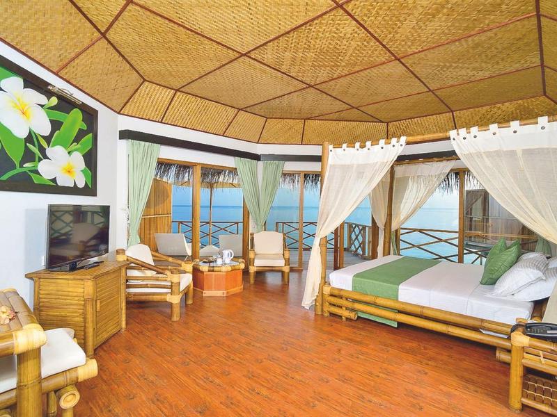 Helles Hotelzimmer mit Holzdecke, Doppelbett, Sitzecke und Blick aufs Meer.