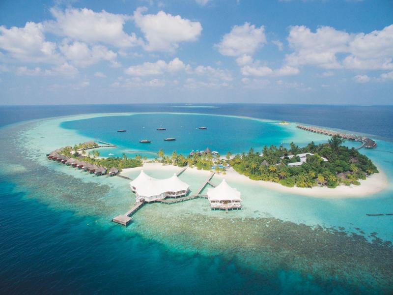 Inselresort mit weißen Sandstränden, Bungalows über dem Wasser und Booten im klaren blauen Meer.