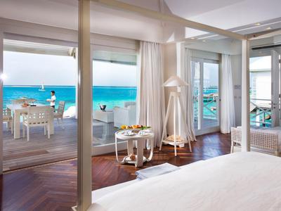 Helles Schlafzimmer mit Meerblick, Terrasse, weißer Einrichtung und Holzboden.