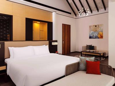 Modernes Schlafzimmer mit großem weißen Bett, Holzakzenten, zwei Nachttischen und Deckenlampe.