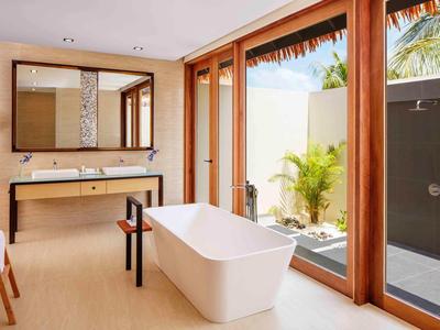 Helles Badezimmer mit freistehender Badewanne, Doppelwaschbecken und großen Glasfenstern zum Garten.