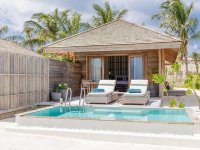 Modern bungalow with private pool, sun loungers, and palm trees in a sunny outdoor area.