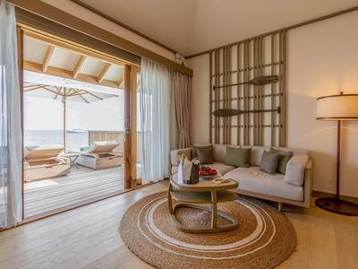 Světý obývací pokoj s pohovkou, kobercem a přístupem na terasu s výhledem na moře.