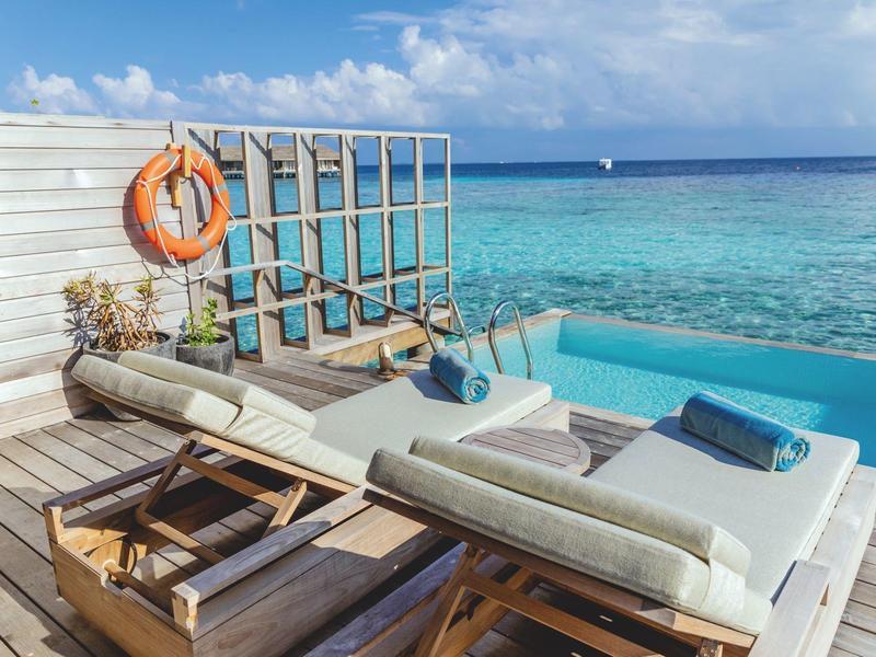 Luxusní lehátka vedle nekonečného bazénu s výhledem na tyrkysové moře.
