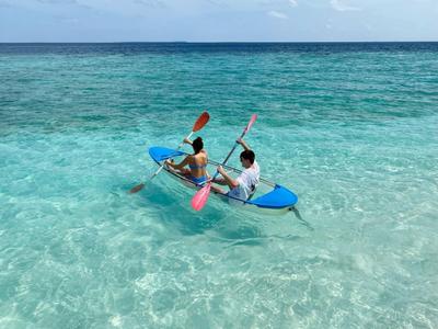 Dos personas remando en un kayak sobre agua clara y turquesa.