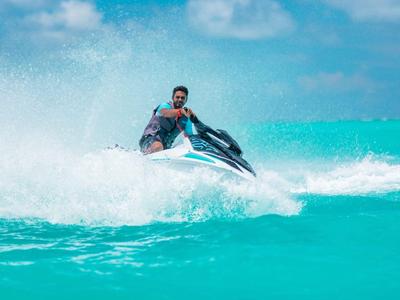 Persona montando una moto acuática en aguas turquesas tranquilas bajo un cielo despejado.