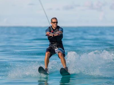Hombre practicando esquí acuático en mar tranquilo bajo cielo despejado.