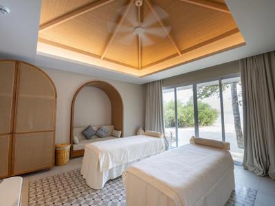 Brightly lit therapy room with two treatment tables and a view of a garden.
