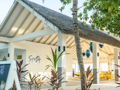Modern white building with thatched roof surrounded by plants in a tropical hotel setting.