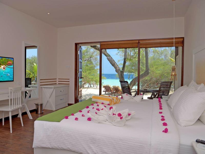 Bright hotel room with large bed, sea view, and terrace with hammock.