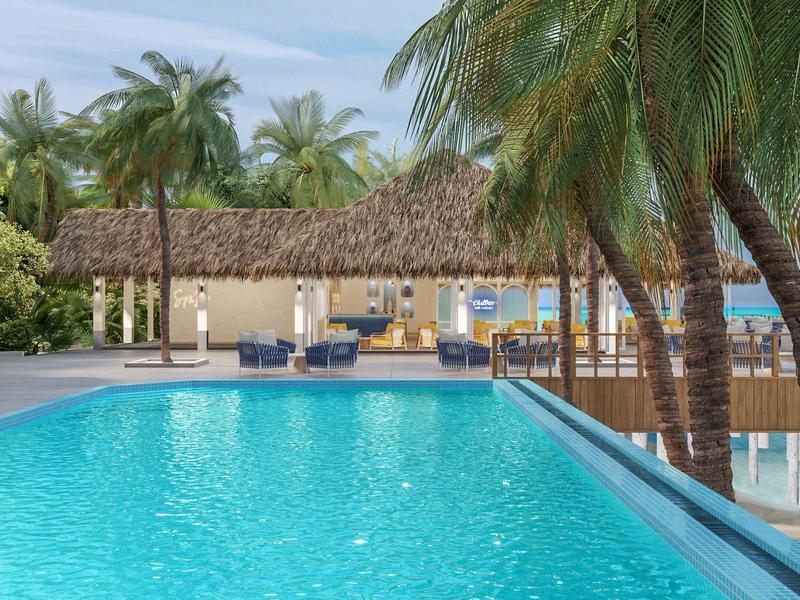 A tropical pool area with palm trees and a bar-like pavilion by the water.