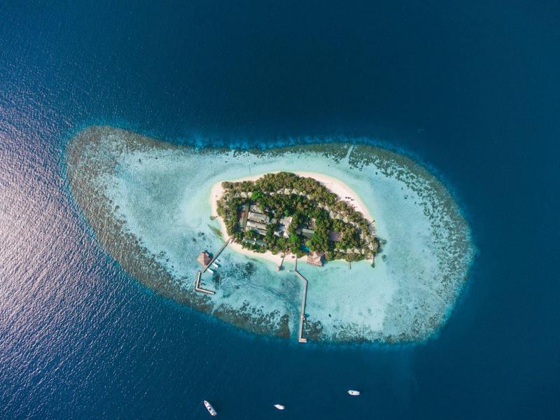 Aerial view of a small tropical island with lush vegetation and surrounding turquoise water.