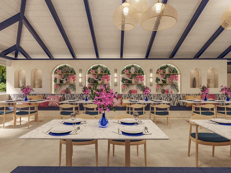 Bright restaurant with blue accents, wooden tables, and floral arrangements on the tables.