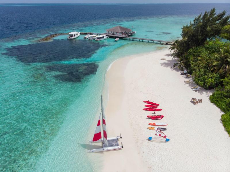 Dreamy white sandy beach with clear turquoise water and colorful kayaks.