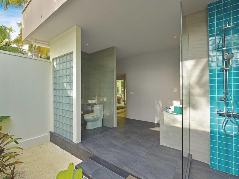 Espace extérieur moderne avec douche et lavabo, entouré de murs et de blocs de verre.