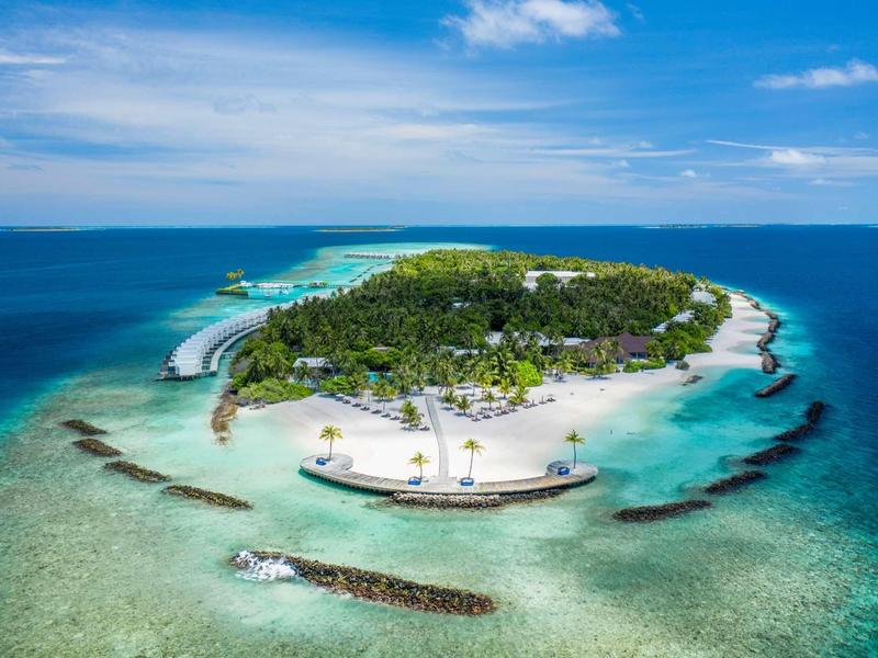 Île tropicale avec plage de sable blanc, végétation verte et eau bleue claire