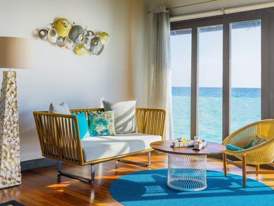 Salon lumineux avec vue sur la mer, canapé, chaises et décoration moderne.