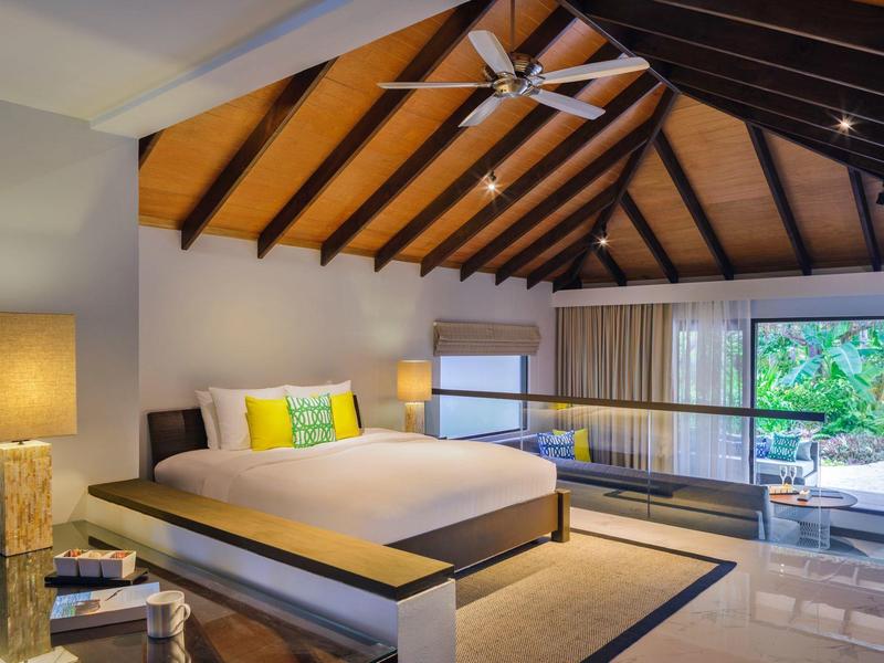 Chambre moderne avec plafond en bois, grand lit et façade vitrée donnant sur le jardin.