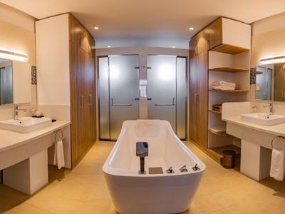 Helles, modernes Badezimmer mit freistehender Badewanne, Doppelwaschbecken und zwei Duschen.