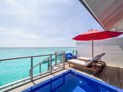 Balkon mit Liegestuhl, rotem Sonnenschirm und Meerblick am Hotel.