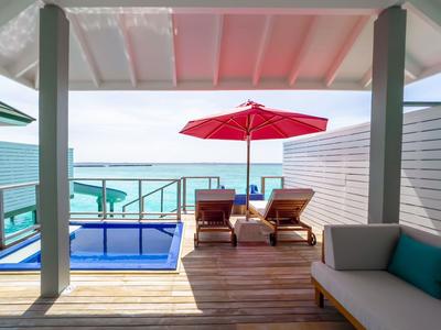 Terrasse mit Pool, Liegestühlen und rotem Sonnenschirm mit Meerblick.