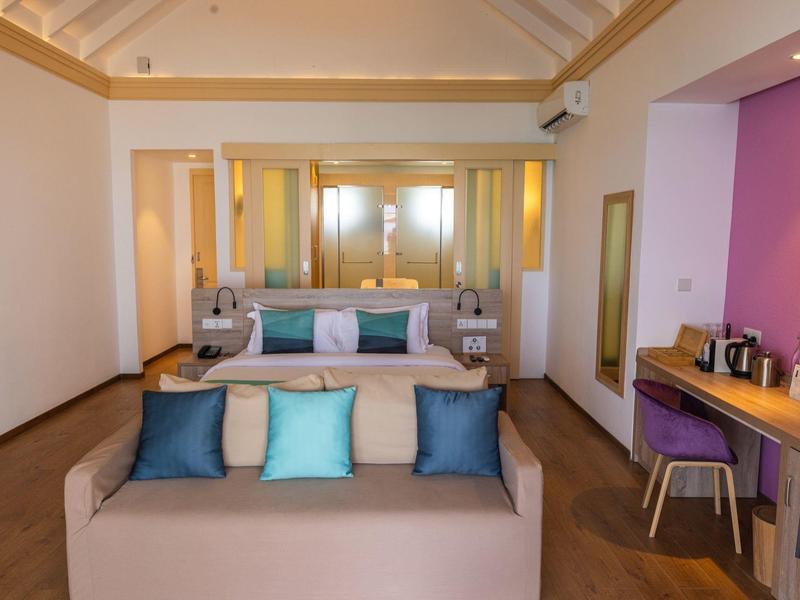 Modern eingerichtetes Hotelzimmer mit Sofa, Schreibtisch und großen Spiegeln.