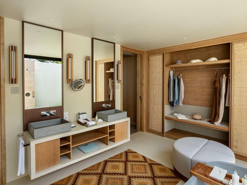 Modern hotel room entrance area with wooden furniture and mirrors