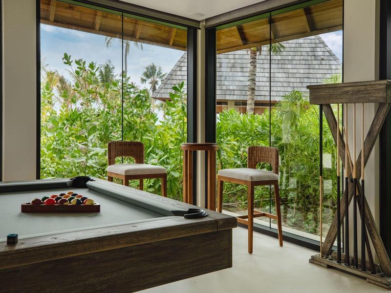 Modern pool table in a bright room with large windows and garden view.