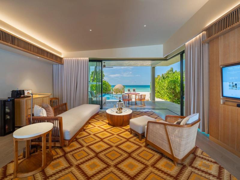 Modern hotel room with sea view, open balcony, and comfortable furnishings.