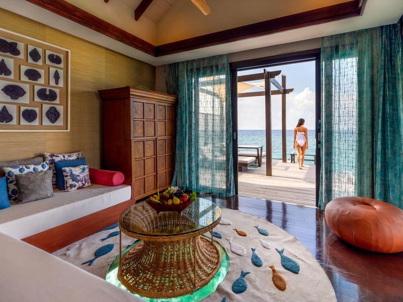 Habitación de hotel acogedora con vista a la piscina y al mar, muebles de madera y decoraciones coloridas.