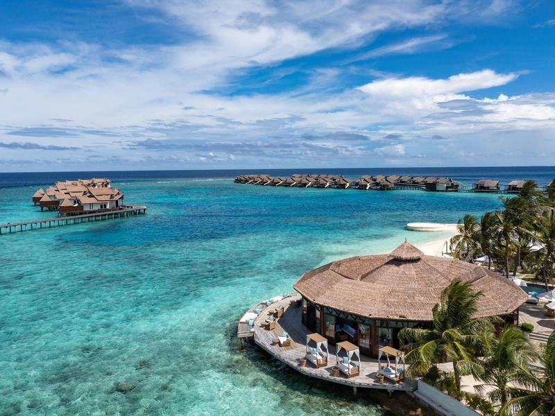 Vista de un hotel de lujo con palmeras y agua azul clara en la playa tropical.