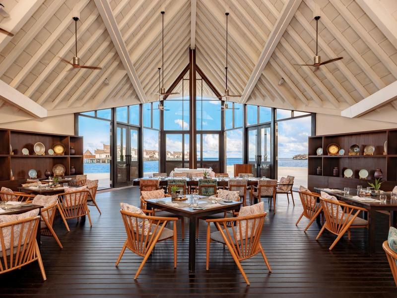 Restaurante elegante de hotel con muebles de madera, ventana grande y vista al agua y montañas