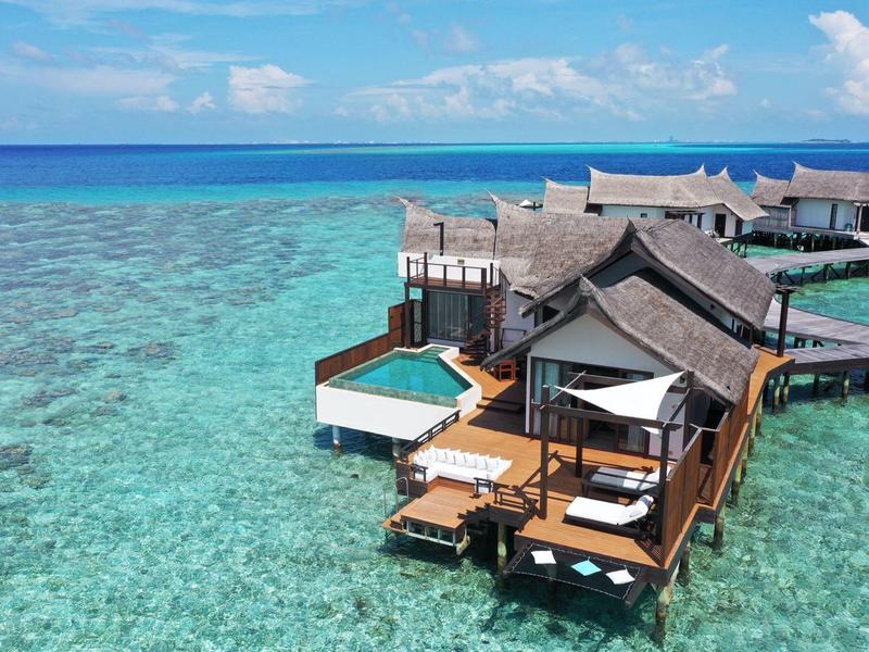 Bungalows de lujo sobre pilotes en agua turquesa clara en un día soleado.