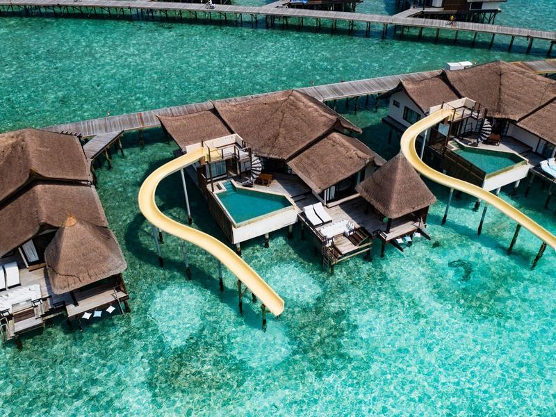 Bungalows con toboganes sobre agua turquesa en un resort sobre el mar.