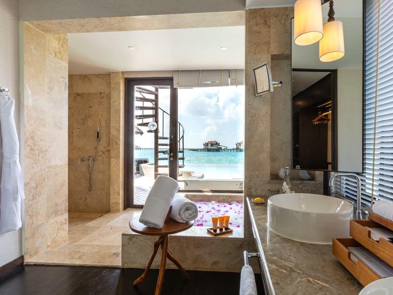 Área de baño moderna con vista a la playa y el mar a través de la puerta abierta en la habitación del hotel.