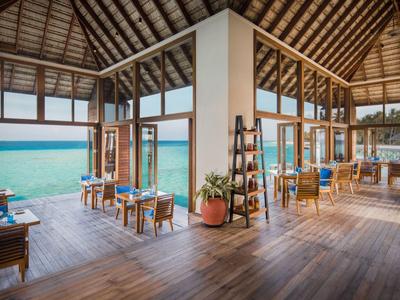 Großzügiger Innenbereich mit Holzfußboden und großen Fenstern mit Meerblick.