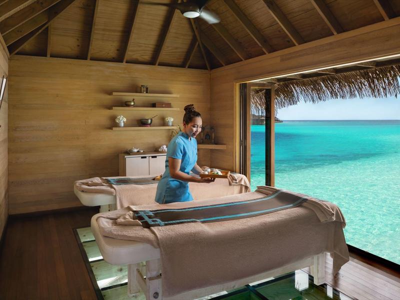 Massageraum mit Aussicht auf das türkisfarbene Meer und Holzwände im Ferienresort