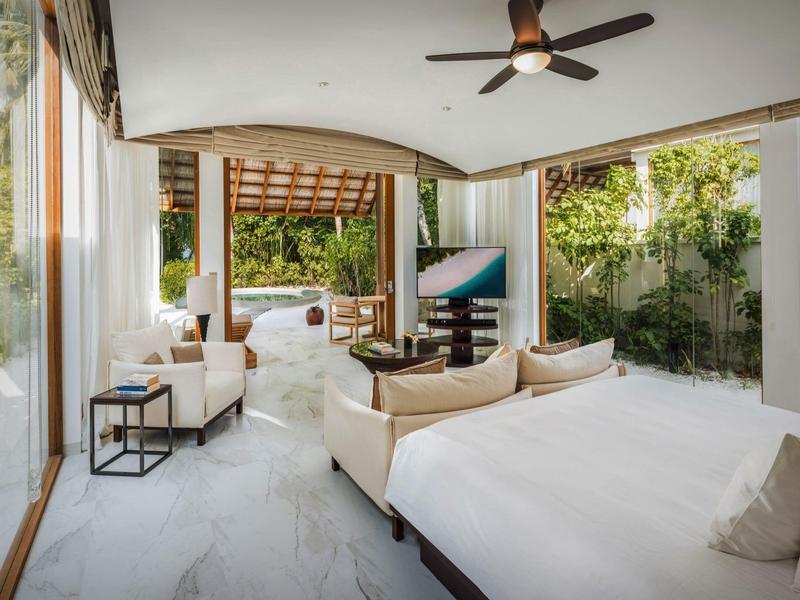 Helles, modernes Hotelzimmer mit offenem Balkon und Blick auf grünen Garten.