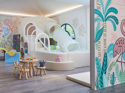 Area giochi colorata per bambini con scivolo, struttura arrampicata e arredi a misura di bambino in stanza luminosa.