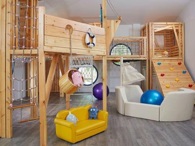 Area giochi per bambini con strutture in legno e sedute colorate all'interno.